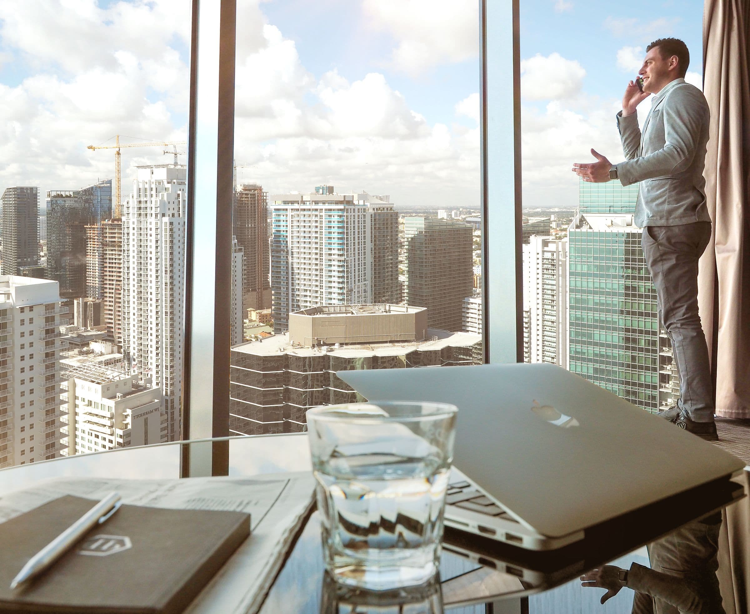 Laptop and notebook on a desk beside a window overlooking the city